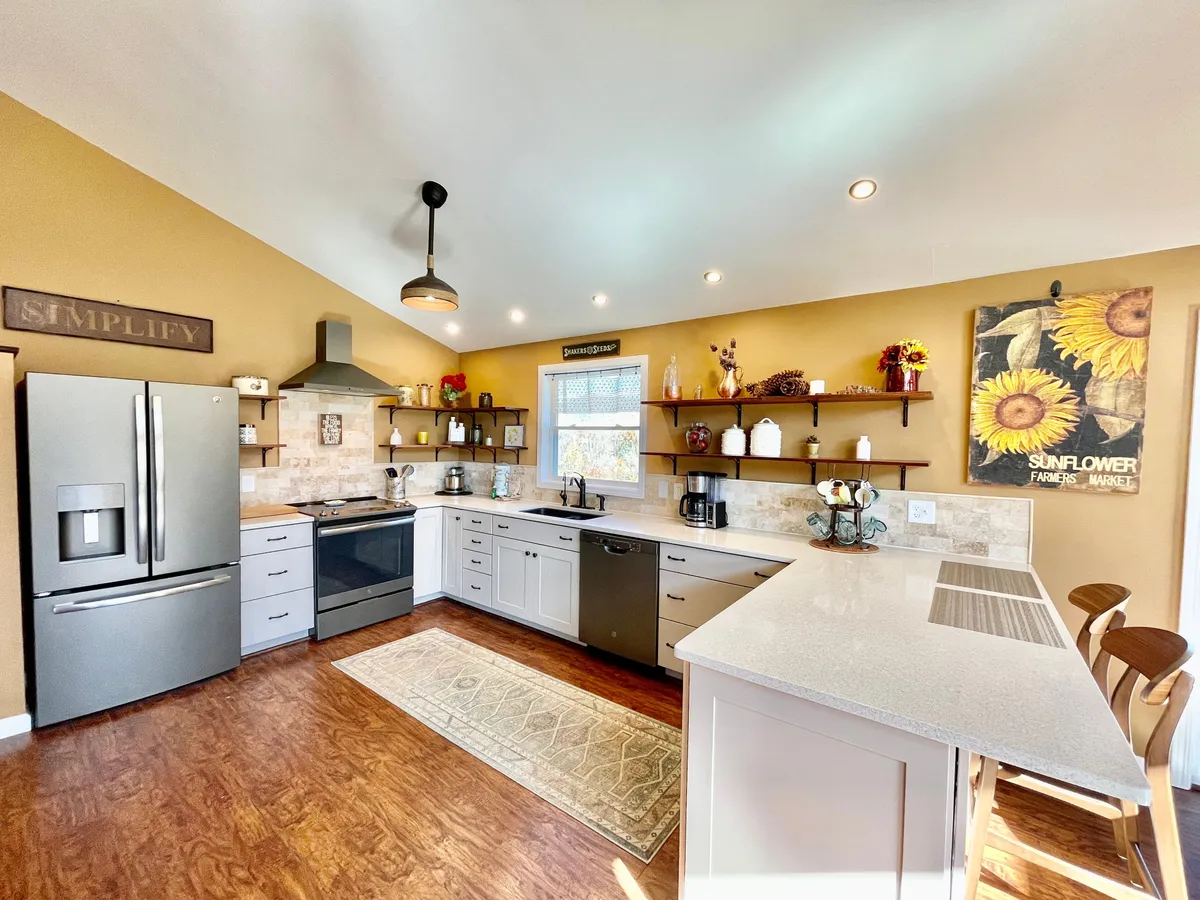 Focusing on the kitchen island and cheerful sunflower artwork, this image presents a vibrant and inviting culinary space. Decorative shelves and a well-lit environment make it easy to imagine breakfast or dinner parties taking place.