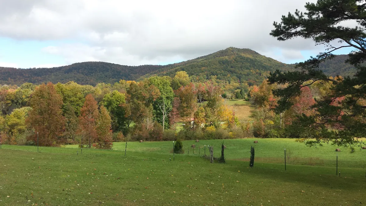 Rolling hills and colorful trees stretch across the landscape with distant mountains visible, evoking the natural beauty and wide-open spaces of the Smoky Mountains. The view is tranquil and inspires thoughts of hiking, picnicking, and outdoor exploration.