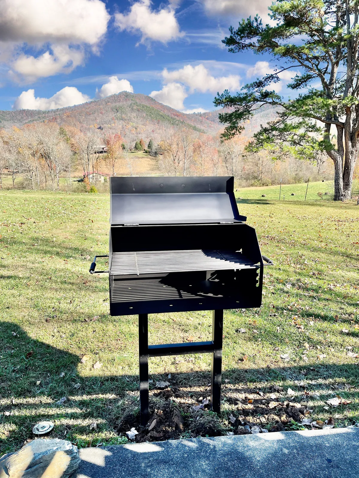 A scenic exterior with a grill in the foreground and sweeping mountain views in the background. The area is set up for barbecuing, outdoor feasts, and group celebrations, suggesting ample space for dining and socializing.