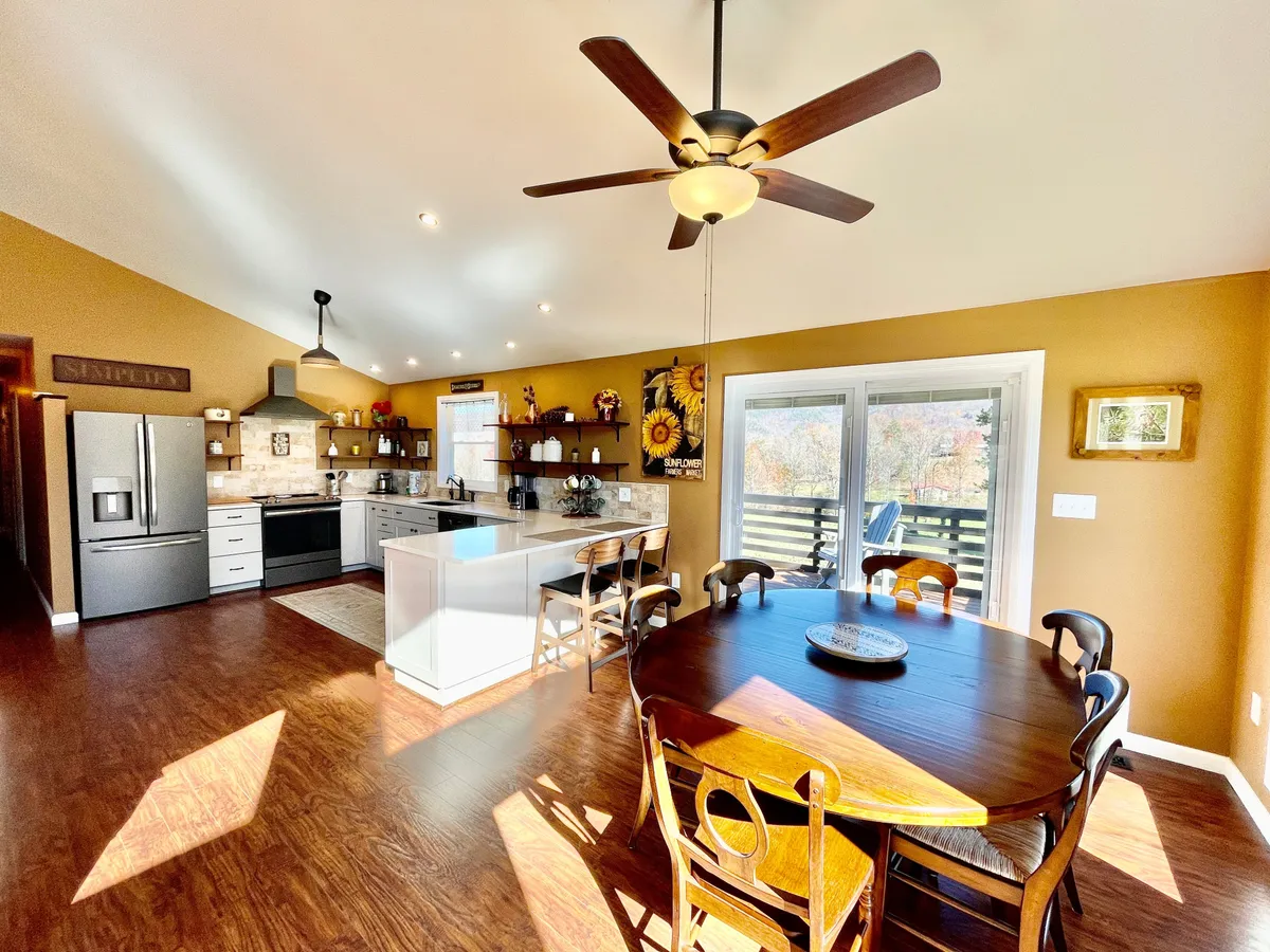 This image captures the heart of the kitchen and dining area, showcasing both the kitchen island and the dining table with a window that invites in natural light. The setup is ideal for meal preparation and family gatherings, with ample space for both cooking and dining. The inviting atmosphere and sight lines between kitchen and dining emphasize togetherness and comfort.