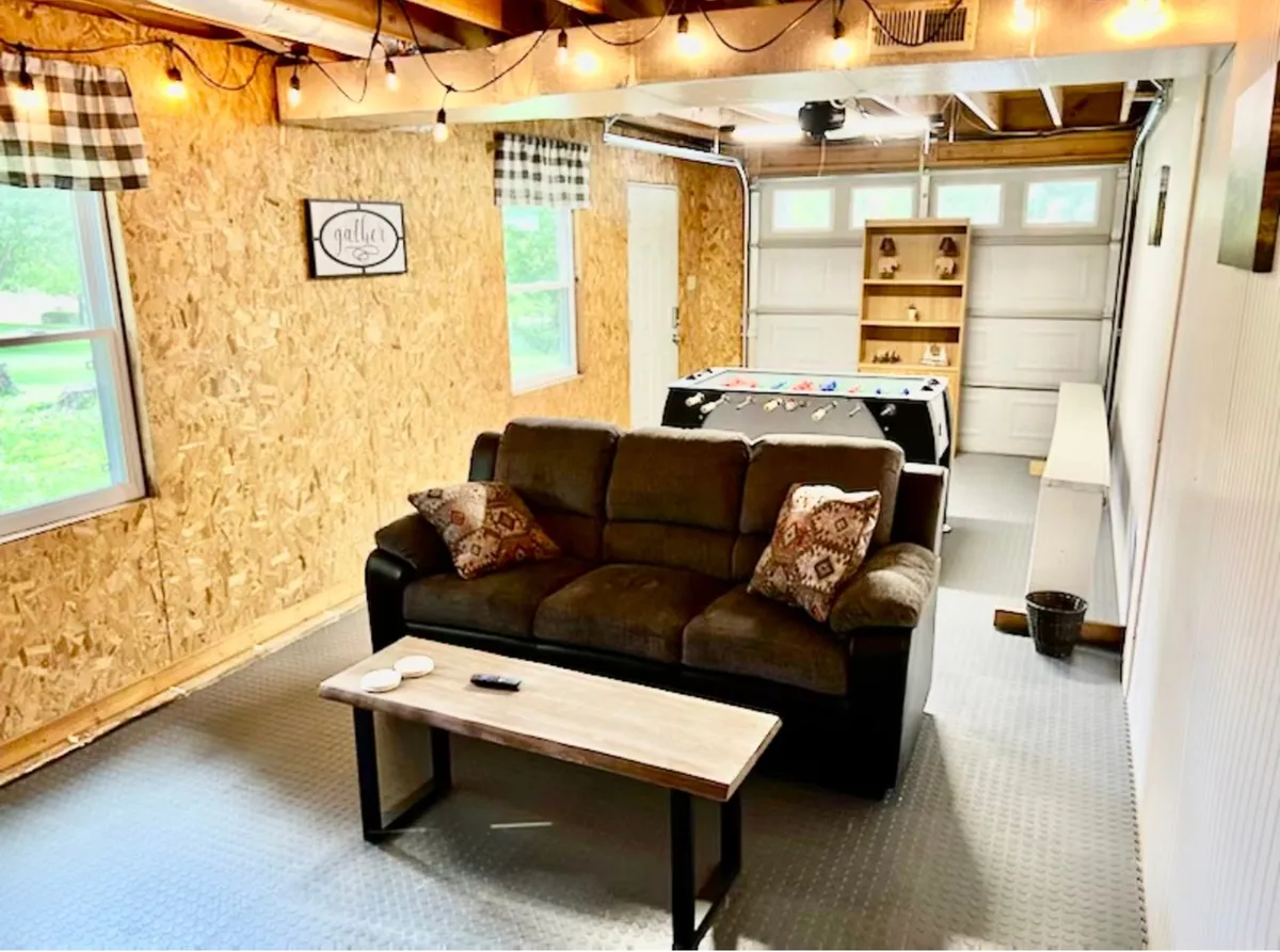A comfortable interior space featuring a sofa, coffee table, and a dedicated game table, accented by playful wall decor. The room is designed for socializing and playing games, with a warm, inviting ambiance ideal for family bonding and laughter-filled evenings.